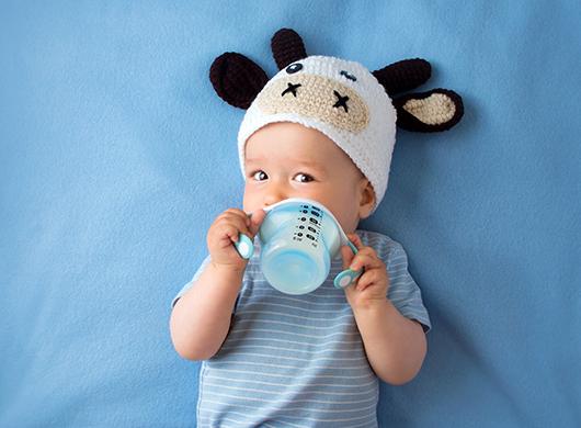 photo of a baby boy wearing a cow cap and drinking milk